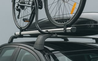 Ein Fahrrad ist auf einem Dachträger auf einem schwarzen Auto befestigt.