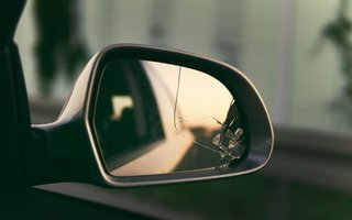 Ein beschädigter Außenspiegel mit sichtbaren Rissen im Spiegelglas